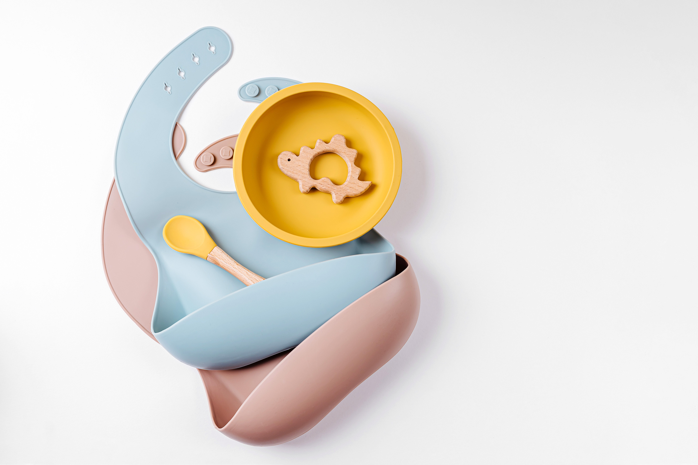 Set of children's tableware and silicone bibs. Baby accessories. Nutrition and feeding concept. Top view, flat lay