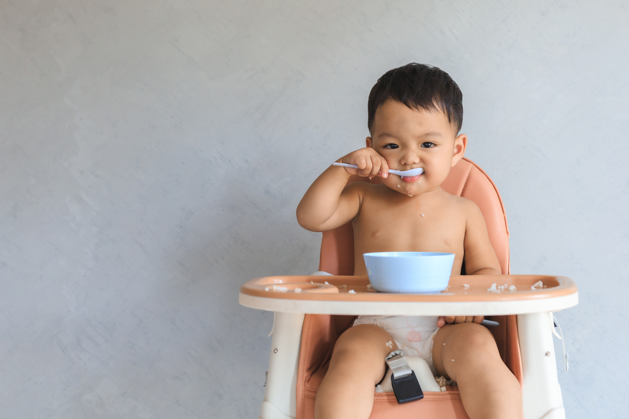 Asian baby boy eating food by himself